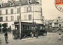 Carte postale en noir et blanc ; des enfants posent pour la photo devant le véhicule.