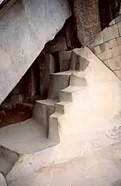 Grotte au Machu Picchu, qui abrite également des portes qui ne mènent nulle part, qui forme un « V » inversé comme la grotte de Naupa Iglesia, et devant laquelle il y a aussi un motif de marche