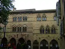 photo couleur de façades de maison en pierre à fenêtres géminées en ogive.