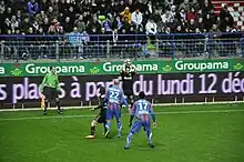 Joueur s'apprêtant à faire une remise en touche. Deux adversaires et un coéquipier sont visibles.