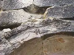 Photographie en couleurs d'une arcature en pierre gravée.