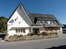 Bâtiment composé de deux parties perpendiculaires, aux murs blancs et au toit d'ardoise bleue. Ses angles, les entourages de fenêtres et le muret devant le bâtiment sont en granit brun.