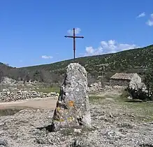 Pointe sommitale du menhir du Lacan des Lavagnes (Hérault, France), amputée et surmontée d'une croix.