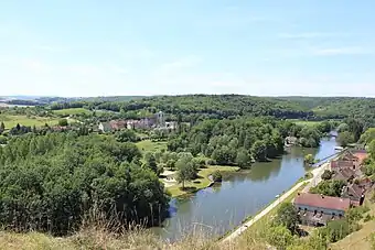 Une rivière traversant un paysage de forêts vallonné, d'où sort un village.