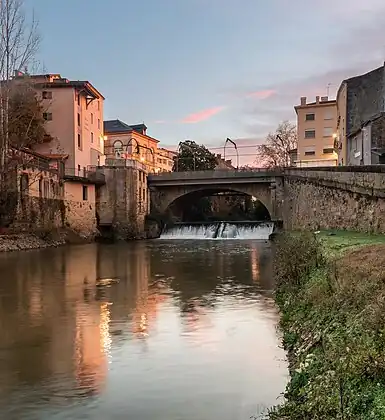 Photo prise à l'aube en aval du pont. La minoterie et le théâtre de Mont-de-Marsan sont visibles sur la gauche et la cale de l'Abreuvoir sur la droite, donnant accès au  port de Mont-de-Marsan, actif jusqu'en 1903.