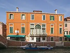 Photo couleur d'une façade de maison orangé au bord d'un canal