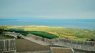 Un promontoire au-dessus de champs cultivés, avec vue sur la mer.