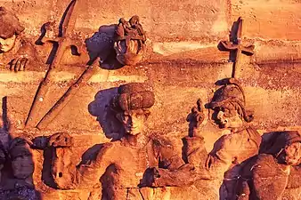 Mur en grès rose duquel émergent des statues de dignitaires et de soldats.