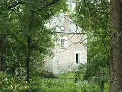 Photographie en couleurs d'un édifice carré surmonté d'une toiture pyramidale établi sur un cours d'eau.