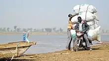 Moto transportant des marchandises sur la rive du fleuve Logone