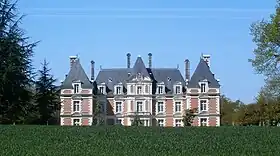 Photographie en couleurs de la façade en pierres et briques d'un château.