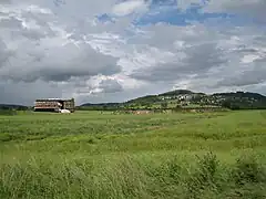Bâtiment du MuséoParc Alésia dans la plaine des Laumes, au pied du village d'Alise-Sainte-Reine. À l'arrière-plan : le Mont-Auxois.
