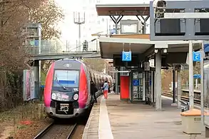 Cliché en couleur. Une rame automotrice se trouve à quai ; des voyageurs y montent.