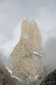 Pic montagneux, entouré par une vague de brume, saupoudré de neige