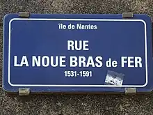 Plaque rectangulaire portant, en blanc sur fond bleu, l'inscription : île de Nantes ; RUE LA NOUE BRAS de FER ; 1531-1591
