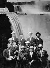 Une douzaine d'afro-américains sont assis avec les chutes du Niagara en arrière-plan