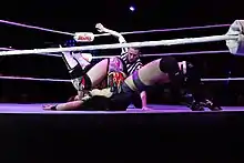 Une catcheuse effectue une german suplex sur son adversaire.
