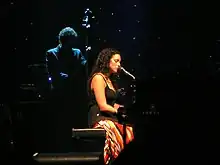 photo d'une femme en robe noire assise derrière un piano.