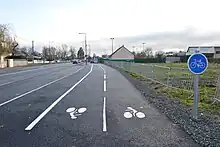 Piste cyclable avec, en arrière-plan, la route départementale