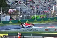 Photographie d'une monoplace rouge et blanche dépassant au freinage une monoplace rouge, vues de profil.