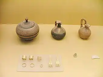 De g. à d., pyxis globulaire, œnochoé-lécythe, aryballe. Pendants d'oreille et bagues. Tombe d'une femme enceinte riche. Vers 850.Musée de l'ancien Agora
