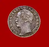 Pièce de monnaie de couleur argentée montrant le profil d'un homme moustachu.