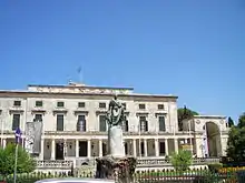 Grand bâtiment à péristyle devant lequel se trouve une statue de bronze