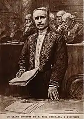 Dessin d’un homme se tenant debout, devant d’autres hommes : en habit vert d’académicien, il tient des feuilles dans sa main droite et semble discourir