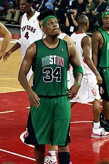 Paul Pierce avec l'uniforme vert et noir des Celtics de Boston regardant en l'air lors d'un match contre les Raptors de Toronto. On aperçoit au fond de l'image Chris Bosh, le numéro 4 de Toronto.