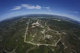 Plusieurs constructions dispersées au milieu d'un site cerné d'une roue avec en arrière plan des collines