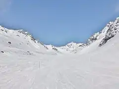 Photographie de la piste de ski Bouchet à Orelle avec des piquets rouges et des montagnettes en neige.