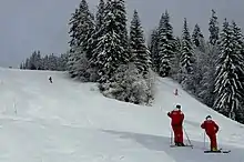 Deux moniteur de l'École du ski français surveillent une leçon de ski d'enfants en classe de neige.
