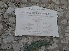 Plaque de marbre, portant l’inscription : "La ville d’Antibes aux victimes de l’Atlantique I, hydravion de grande ligne tombé en mer devant ce port le 19 mai 1937. Bourdin Lucien (chef pilote), Juin Marcel (contrôleur direction du matériel de la compagnie Air France), Brochet Luce (second-maître mécanicien de la Marine), Blouin Robert (chef de service radio de la compagnie Air France), Rayer Charles (mécanicien naviguant), Cités à l’Ordre de la nation le 21 mai 1937"