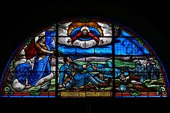 Photographie couleur d'un vitrail montrant le Christ étendant les bras vers des soldats français étendus au sol.