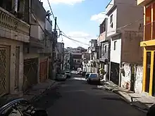 Photographie d'une rue. Des voitures sont stationnées à côté des trottoirs.
