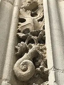 Sculpture d'un coquillage en dessous d'une feuille de vigne.