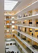Vue de l'intérieur d'un édifice (un musée) : les nombreux étages sont ouverts sur une zone centrale ; les tons sont blancs et l'ensemble lumineux.