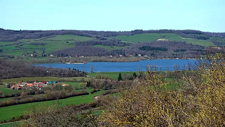 Le lac de Panthier vu depuis Châteauneuf.La rive opposée est essentiellement sur Créancey. De l'autre côté du lac, deux petits monts entièrement recouverts de bois : le Petit Montot (butte de gauche, ~420 m d'alt.) sur Créancey et à sa droite le Grand Montot (446 m d'alt.) sur Semarey, commune non limitrophe du lac. Les berges à droite derrière les arbres sont sur Commarin. Sur l'avant à gauche, le hameau des Bordes sur Vandenesse.