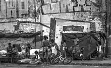 Sur un trottoir, une dizaine de personnes se côtoient dans une ambiance familiale.