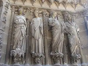 Quatre statues contre des colonnes encastrées : l'ange regarde la Vierge, une seconde Vierge est tournée vers Élizabeth.