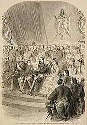 Personnalités assises avec groupe d'hommes debout derrière.