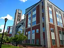 Immeuble de 5 étages en briques rouges à parements blancs, une tour avec une horloge à l'un de ses angles.