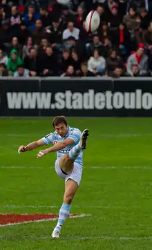Photo d'un homme de face, venant de frapper un ballon qui se trouve devant lui en l'air.
