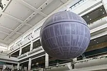 Une maquette d'une station spatiale ronde sur un fond noir.