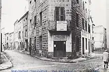 Angle de deux rues bordées d'immeubles à deux étages.