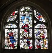 Baie 12Début XVIe . XXe siècle. Composition : 3 lancettes plein cintre, tympan à 2 ajours. Hauteur : 2,50 m, largeur : 2,10 m. Fragments : bordures, architecture, têtes, partie d’un saint portant une épée, début XVIe siècle.