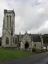 Photographie d'une église avec, de gauche à droite, la tour surmontant une chapelle, une lucarne, un porche sculpté, puis le chevet