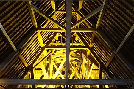 Charpente en bois éclairée par des lampes.