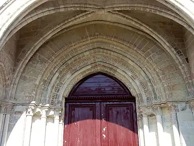 Porte rouge surmontée de volutes et d'une croisée d'ogives.