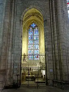 Haute pièce surmontée d'une croisée d'ogives et fermée une grille en fer forgée. Une verrière bleutée représentant une quinzaine de personnages donne dans vers l'extérieur.